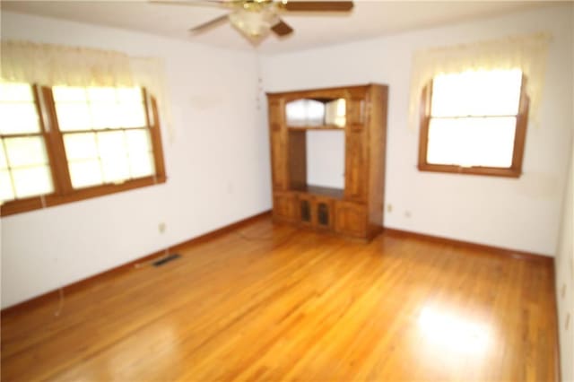empty room featuring baseboards, a ceiling fan, and light wood finished floors