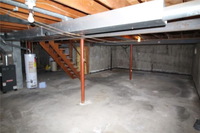 unfinished basement featuring water heater and stairway
