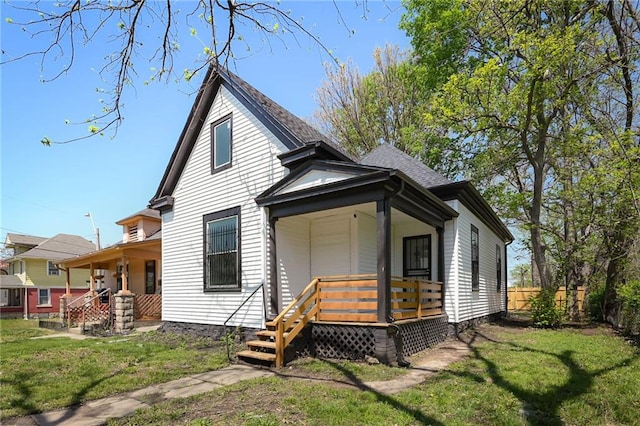 rear view of house with a lawn, a porch, and fence
