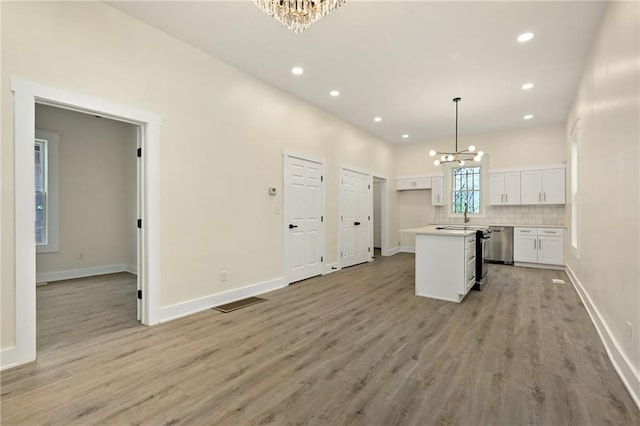 kitchen with stainless steel dishwasher, light wood-style floors, a notable chandelier, and white cabinetry