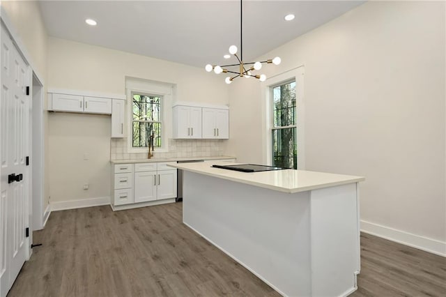 kitchen featuring white cabinets, a notable chandelier, wood finished floors, and a healthy amount of sunlight