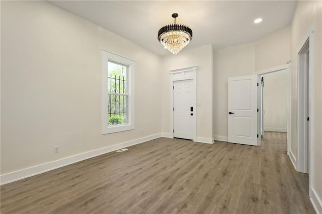 entrance foyer with baseboards, wood finished floors, recessed lighting, and a notable chandelier