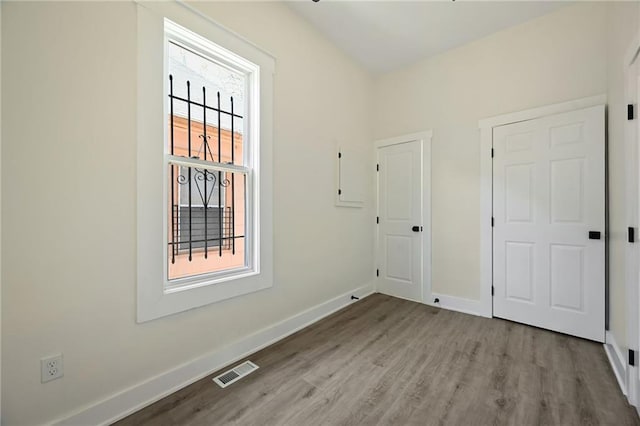 unfurnished room with wood finished floors, visible vents, and baseboards