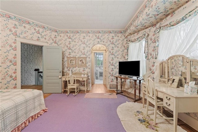 bedroom with arched walkways, wallpapered walls, wood finished floors, and ornamental molding