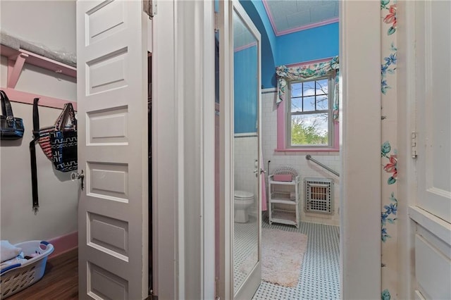 corridor with wainscoting, heating unit, and tile walls