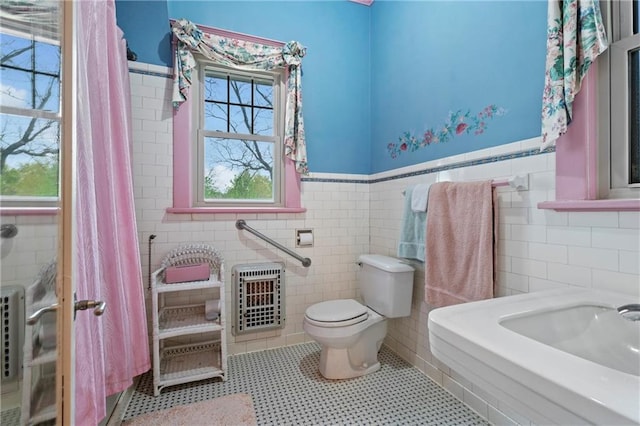 full bath with tile walls, heating unit, a wainscoted wall, and toilet