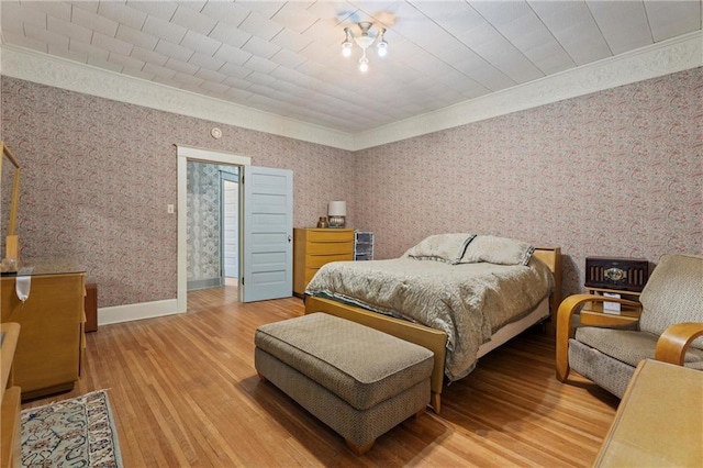 bedroom with wallpapered walls, baseboards, wood finished floors, and crown molding