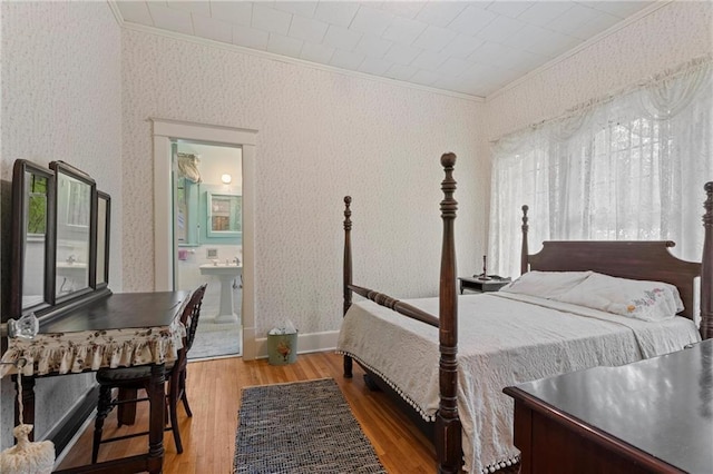 bedroom with ensuite bath, crown molding, wood finished floors, and wallpapered walls