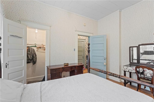 bedroom with ornamental molding, wood finished floors, and wallpapered walls