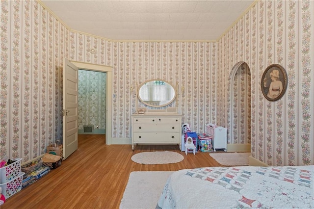 bedroom with wood finished floors, baseboards, and ornamental molding