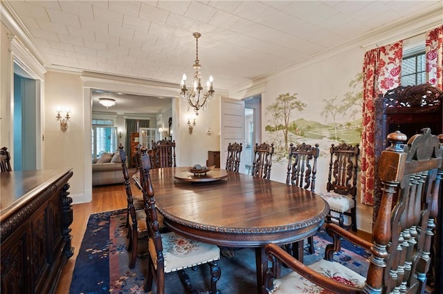 dining area with light wood-style flooring, a notable chandelier, and ornamental molding