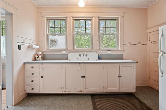 kitchen with light countertops, freestanding refrigerator, and a wealth of natural light