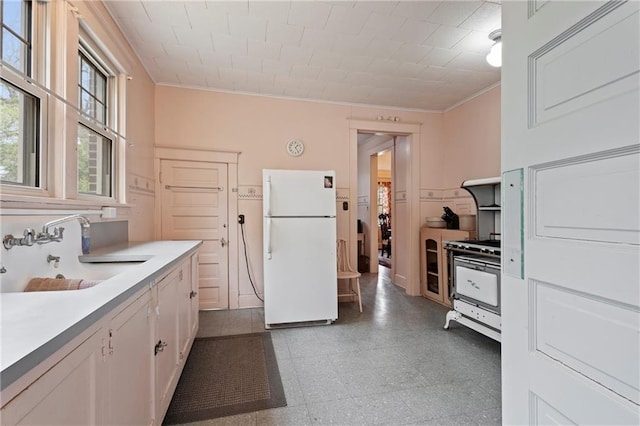 kitchen featuring range with gas stovetop, a sink, light countertops, ornamental molding, and freestanding refrigerator