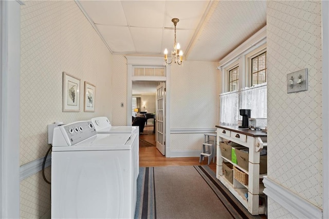 washroom with washing machine and clothes dryer, wood finished floors, wallpapered walls, a chandelier, and laundry area