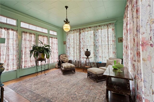 sitting room with ornamental molding and wood finished floors