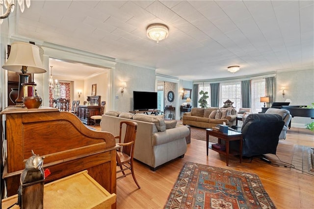 living area featuring light wood-type flooring, a notable chandelier, and ornamental molding