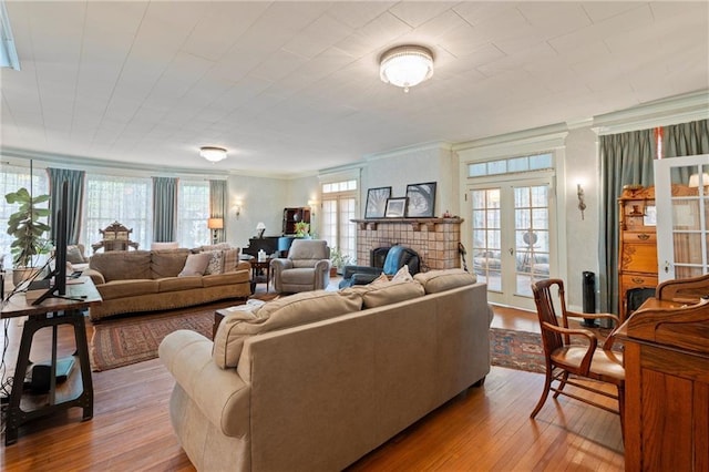 living area with a fireplace, hardwood / wood-style flooring, ornamental molding, and french doors