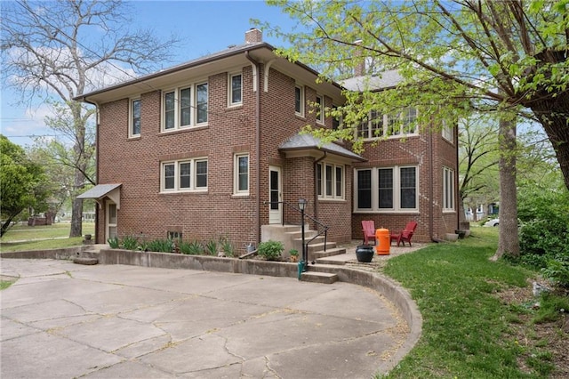 american foursquare style home featuring a front lawn, a chimney, and brick siding