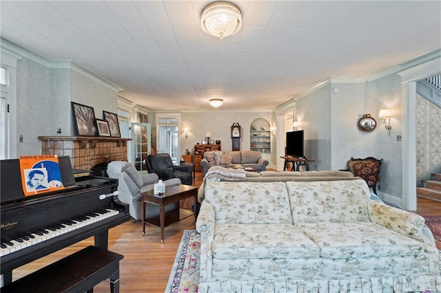 living room featuring built in shelves, light wood finished floors, stairs, and ornamental molding