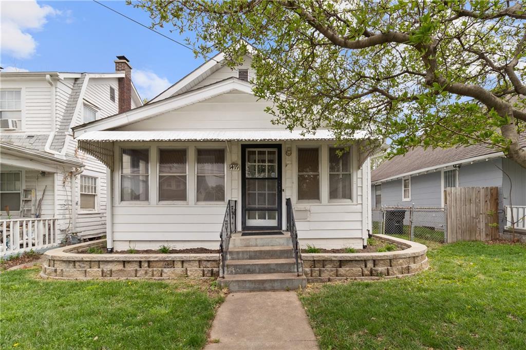 shotgun-style home featuring fence, a front yard, and entry steps