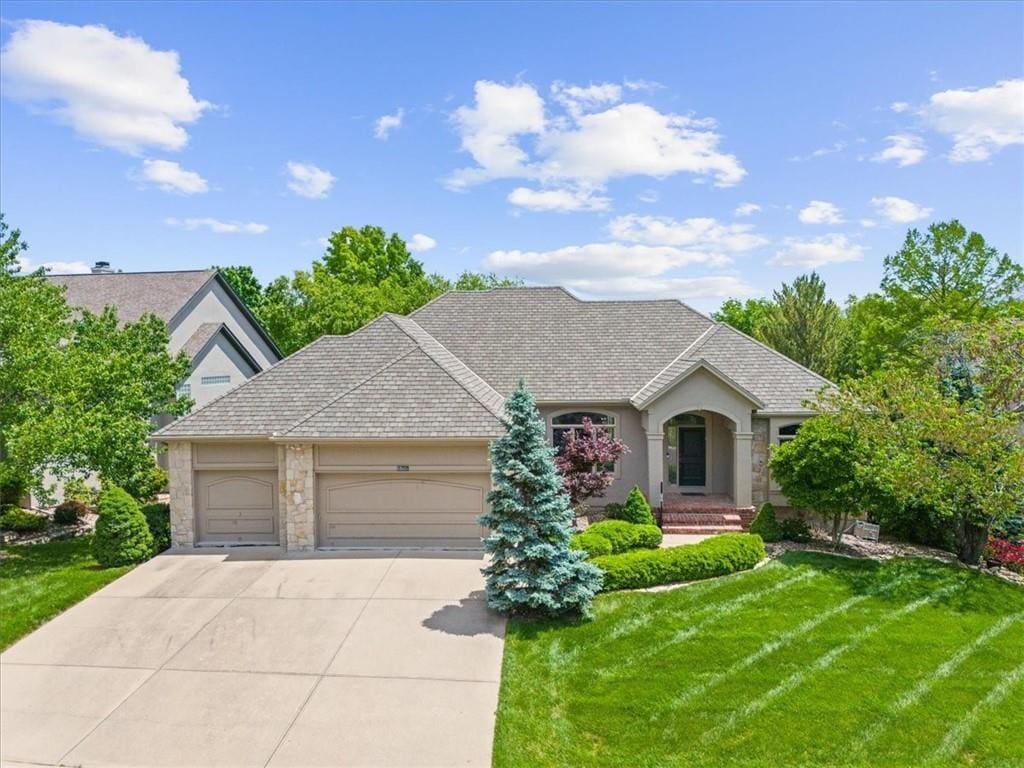 6318 W 128th Pl, Overland Park, KS 66209 - view of front of house with a garage, concrete driveway, a front yard, stucco siding, and stone siding