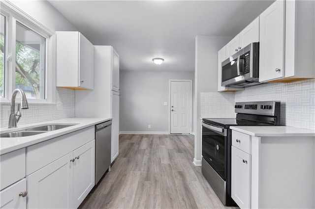 kitchen with decorative backsplash, appliances with stainless steel finishes, light countertops, a sink, and white cabinetry
