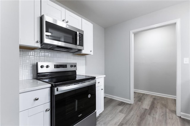 kitchen featuring appliances with stainless steel finishes, decorative backsplash, light wood-type flooring, and light countertops