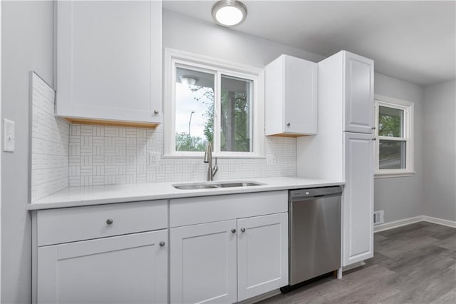 kitchen with tasteful backsplash, light countertops, dishwasher, a sink, and white cabinetry