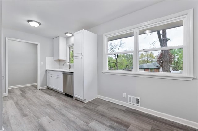 kitchen with baseboards, visible vents, light wood-style floors, and dishwasher
