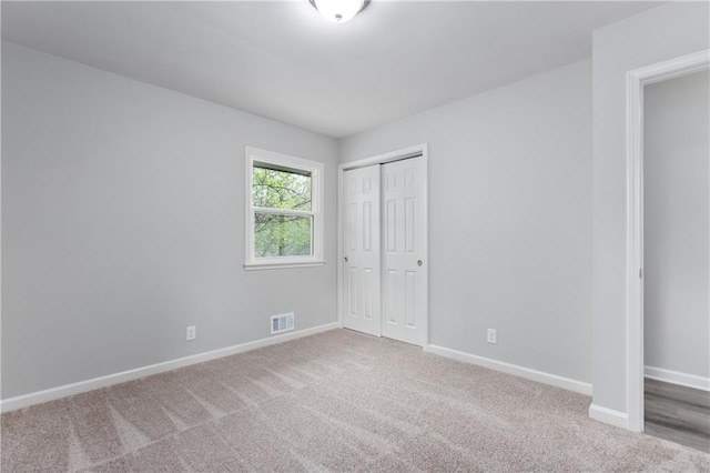 unfurnished bedroom with carpet floors, visible vents, a closet, and baseboards