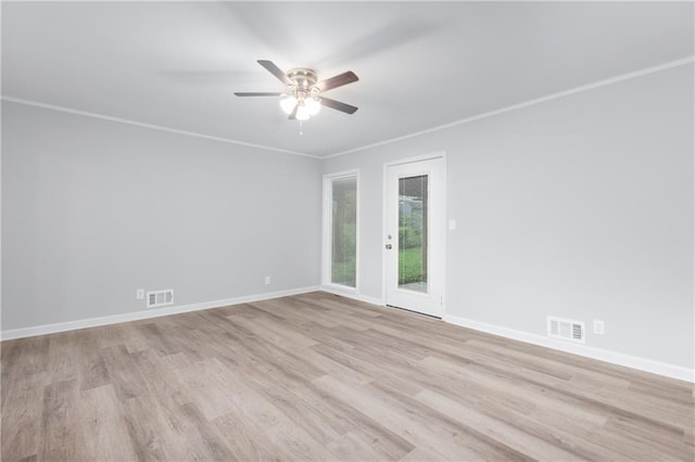 spare room featuring light wood finished floors, a ceiling fan, visible vents, and baseboards