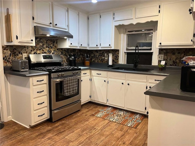 kitchen with stainless steel gas stove, dark countertops, and under cabinet range hood