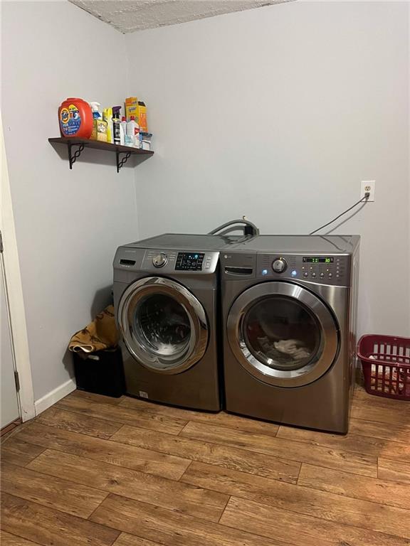 washroom featuring washer and dryer, wood finished floors, and laundry area