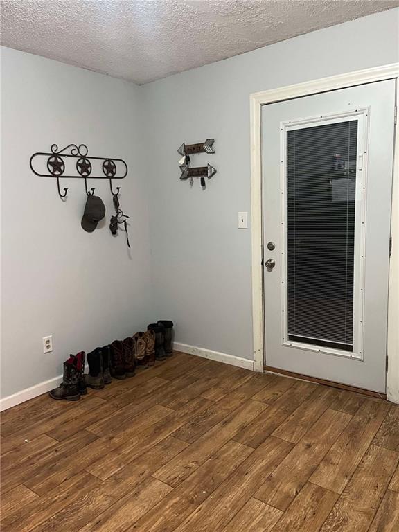 entryway featuring a textured ceiling, hardwood / wood-style floors, and baseboards