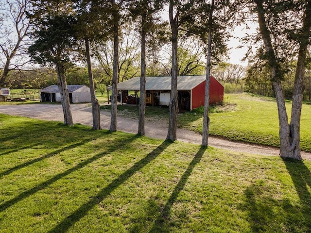 view of yard featuring driveway, a detached garage, and an outbuilding