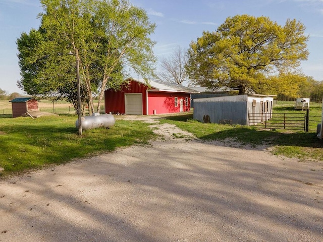 view of pole building with fence, a yard, and dirt driveway