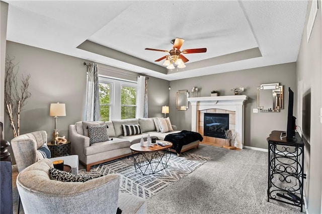 12200 E 214th Ter, Peculiar, MO 64078 - living area with a tray ceiling, carpet flooring, ceiling fan, a tile fireplace, and baseboards