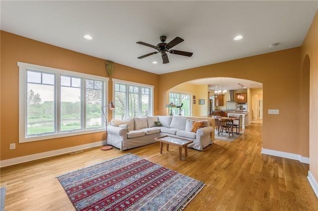 8725 Nebo Hills Rd, Liberty, MO 64068 - living room featuring light wood finished floors, arched walkways, ceiling fan with notable chandelier, baseboards, and visible vents