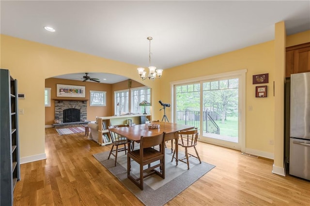 8725 Nebo Hills Rd, Liberty, MO 64068 - dining space with visible vents, a fireplace, light wood-style floors, arched walkways, and ceiling fan with notable chandelier
