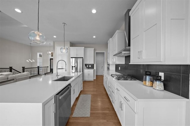 6309 NW 58th Ter, Kansas City, MO 64151 - kitchen with white cabinets, stainless steel appliances, a sink, wood finished floors, and wall chimney range hood
