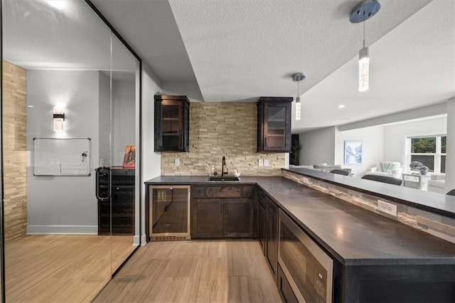 6309 NW 58th Ter, Kansas City, MO 64151 - bar featuring beverage cooler, a sink, stainless steel microwave, light wood-style flooring, and tasteful backsplash