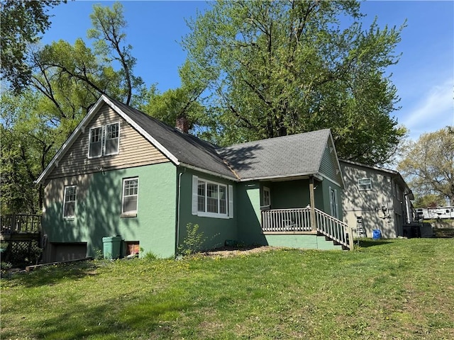 exterior space featuring a lawn, a chimney, covered porch, and stucco siding