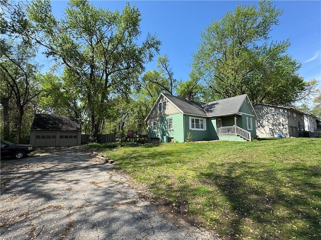 view of side of home with a detached garage, an outdoor structure, a lawn, and covered porch