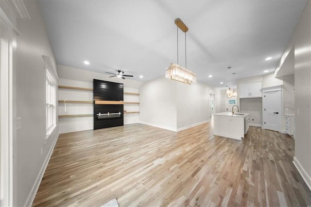 unfurnished living room featuring light wood-style flooring, baseboards, recessed lighting, a ceiling fan, and a large fireplace