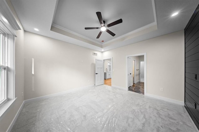 unfurnished bedroom with a raised ceiling, carpet flooring, ornamental molding, ensuite bath, and recessed lighting