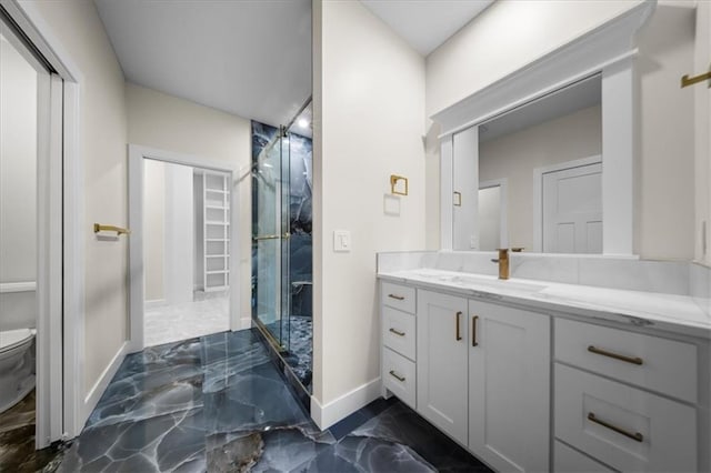 full bathroom featuring marble tiled floors, a shower stall, vanity, toilet, and baseboards