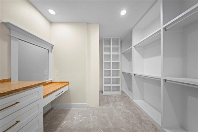 walk in closet with built in desk and carpet floors