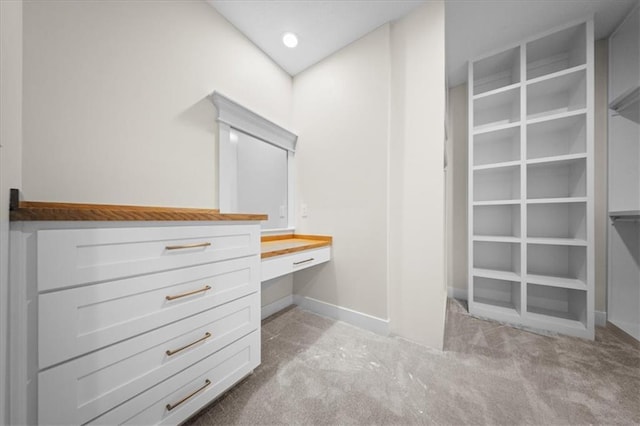 spacious closet featuring built in desk and carpet flooring