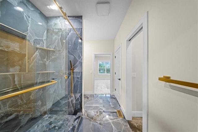 bathroom with marble tiled flooring, a marble finish shower, and baseboards