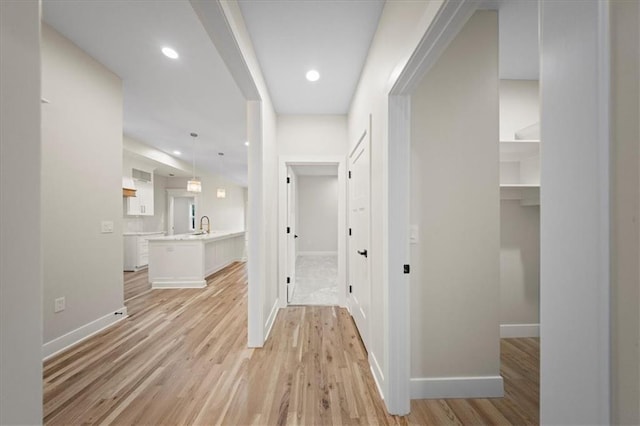 corridor with baseboards, light wood-style flooring, and recessed lighting